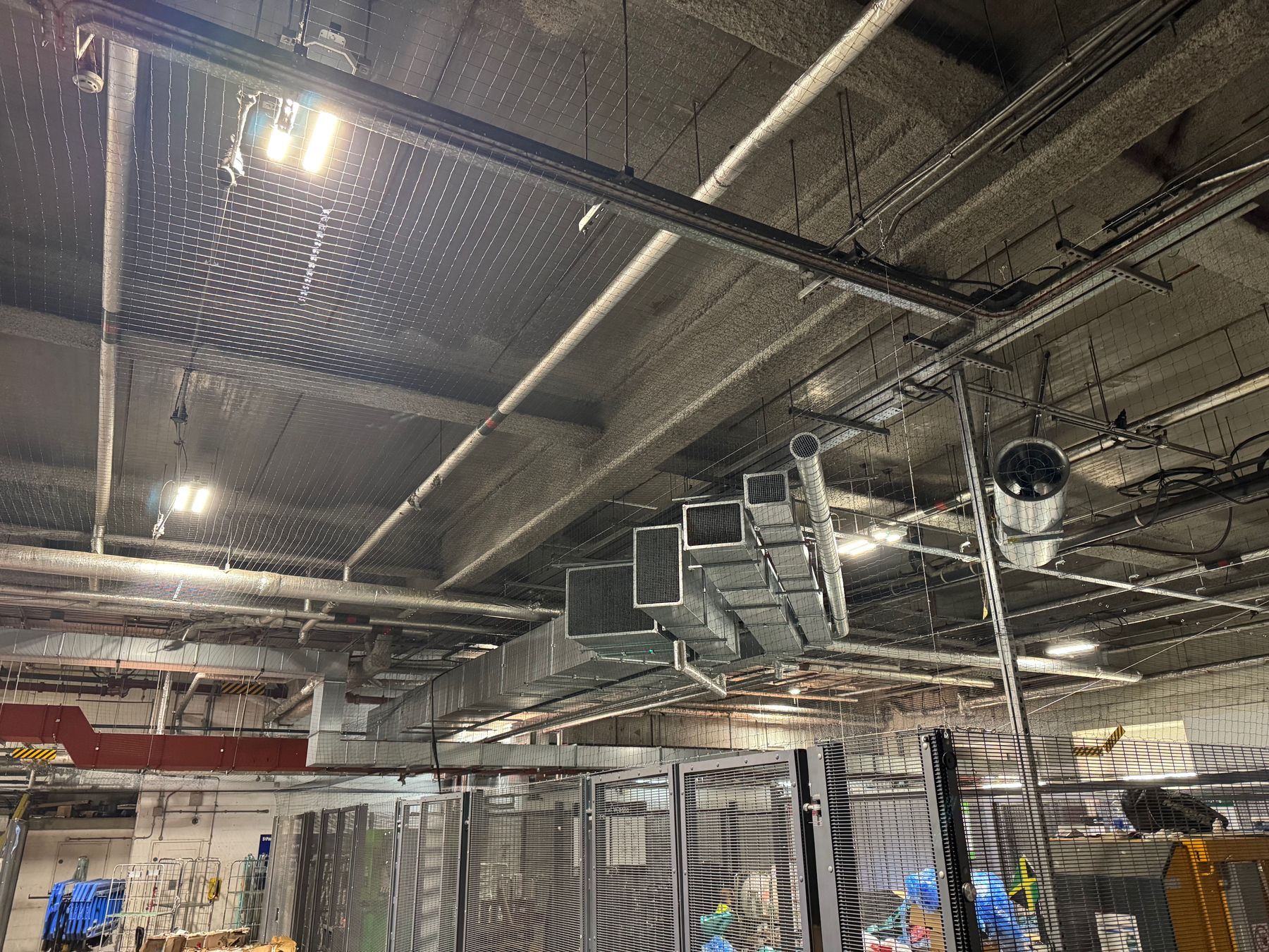 Bird netting under the ceiling of a loading bay, around ducts and pipework